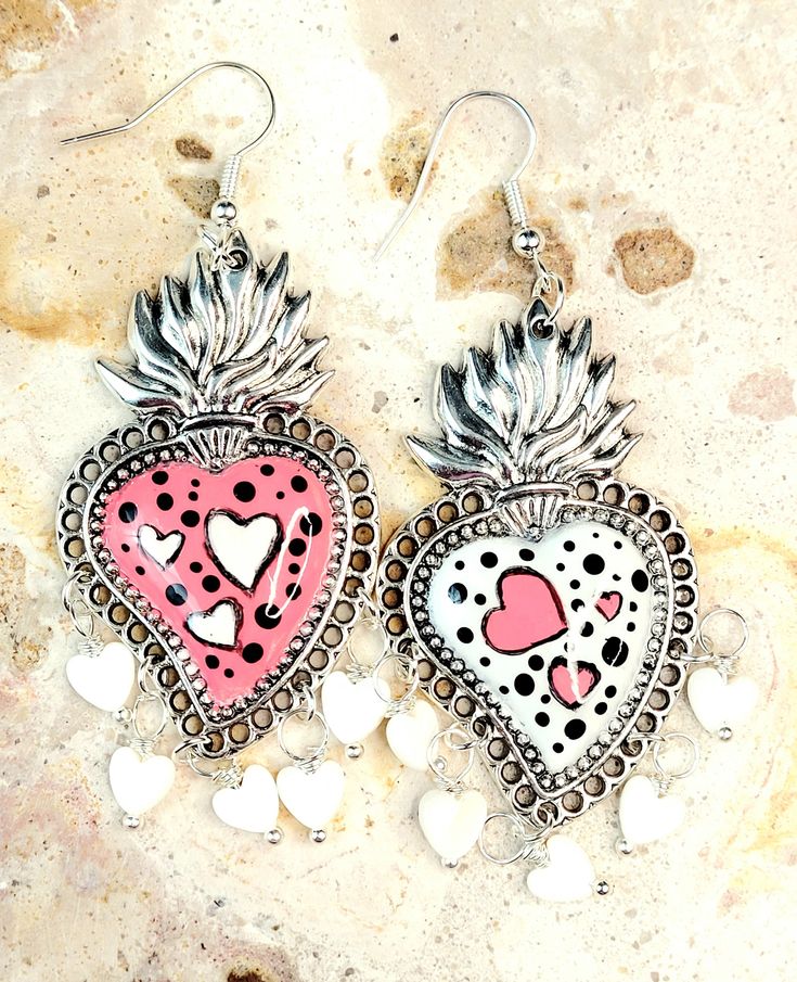 Beautiful and unique handmade earrings delicately brush painted with hearts in white and pink and adorned with natural shell hearts, protected with several layers of jewelry varnish, to protect the paint and make them look even more beautiful. These sacred heart earrings are inspired by Frida Khalo and hand painted, part of our Mexican culture, they are the ideal complement for any occasion that will surely enhance your beauty since they are unique pieces, the ideal gift for Mother's Day and Mother's Day. . holidays and birthdays, or just the special gift for her. Features/ Product info: -Large: 2 in  (Please see the photos, this design comes in two sizes.) The Main Material: Zinc Alloy  (Silver) Color: Pink - Earrings: 3.20 in (H) 1.75 (W) -Earrings weight: 6 grams (each) -The hooks are h Unique Hand Painted Heart Earrings, Unique Hand Painted White Earrings, Pink Hand Painted Heart Jewelry, Pink Bohemian Jewelry For Valentine's Day, Bohemian Pink Jewelry For Valentine's Day, Artistic Hand Painted Jewelry For Valentine's Day, Cute Hand Painted White Jewelry, Whimsical White Jewelry For Valentine's Day, Cute White Hand Painted Jewelry