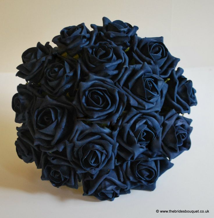 a bouquet of dark blue roses on a white tablecloth with the center surrounded by smaller flowers