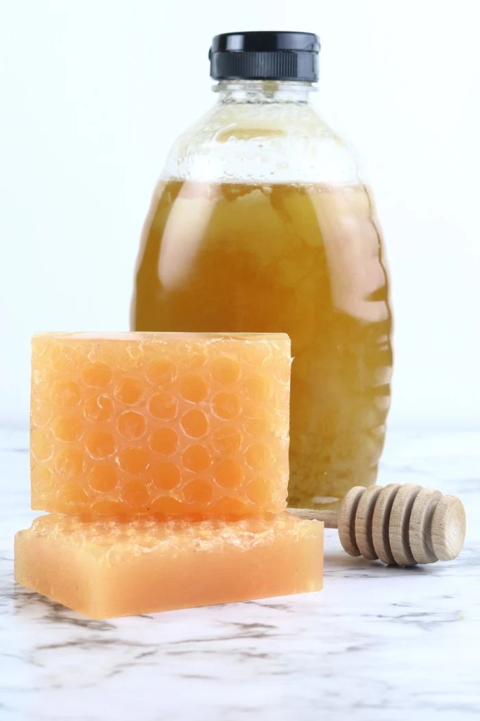 a bottle of honey sits next to a block of soap