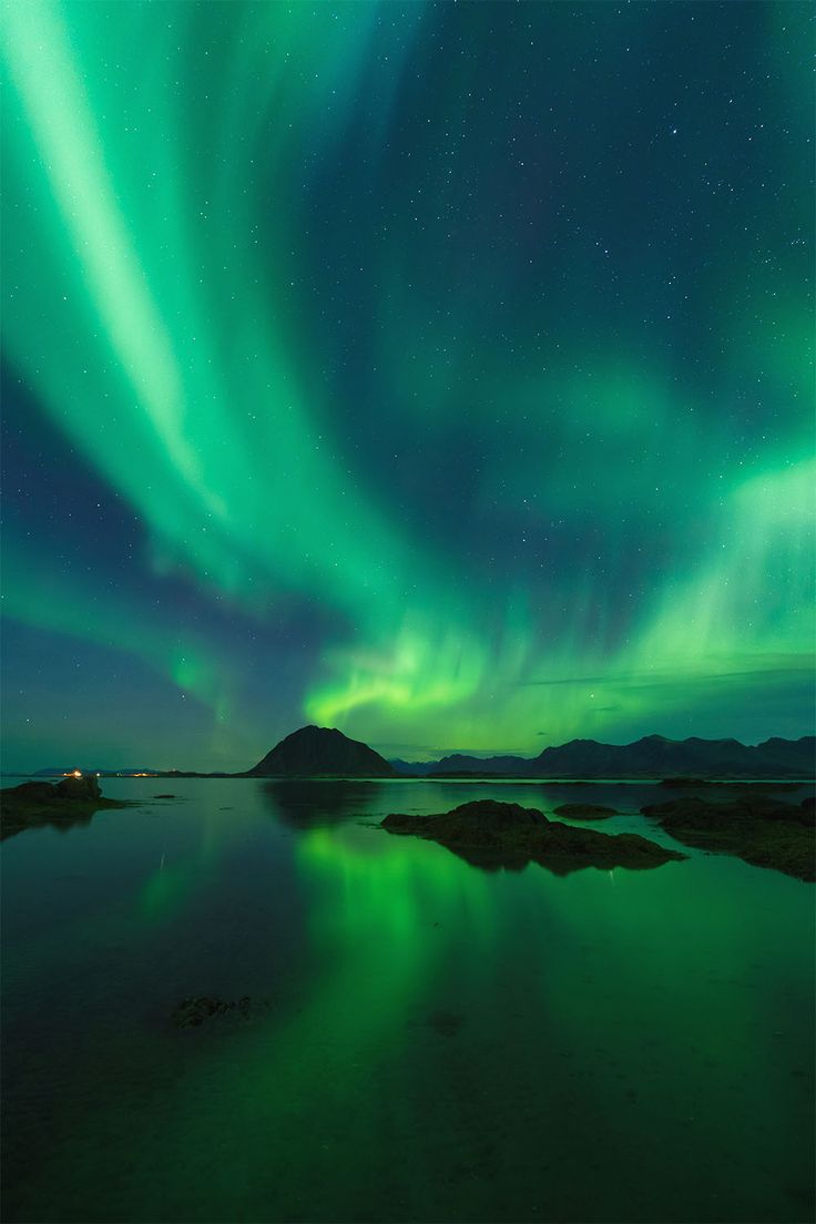 an aurora bore is seen over the water in this green night time scene with stars and clouds