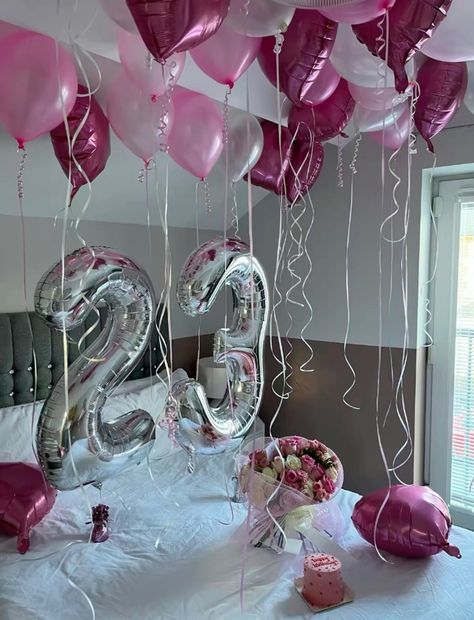 balloons and streamers are hanging from the ceiling in front of a table with a cake