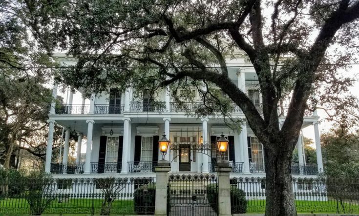 a large white house sitting next to a tree