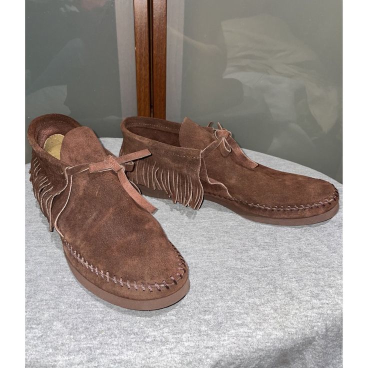 Step Out In Style With These Vintage Quoddy Deerskin Leather Fringe Flat Moccasins Chukka Ankle Boots In Brown. The Boots Feature An Almond Toe Shape, Tie Closure, And Adjustable Strap For Comfort And Ease Of Wear. The Lightweight Design And Rubber Outsole Make Them Perfect For All Seasons, Whether You're Traveling Or Going For A Casual Look. Handmade With Deer Skin And One Of A Kind, The Boots Are Accented With Fringe And A Strap, Giving Them A Hippie, Bohemian, 70s Theme. With A Solid Pattern Western Style Suede Moc Toe Boots, Vintage Suede Moccasins With Round Toe, Vintage Suede Moccasins, Casual High-top Leather Moccasins, Vintage Round Toe Moccasins For Fall, Fall Moccasins With Moc Toe, Western Suede Moccasins For Fall, Western Style Suede Moccasins For Fall, Western Style Closed Toe Moccasins For Fall