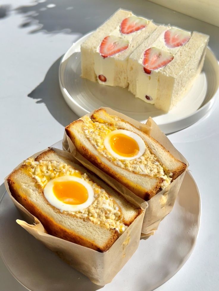 two pieces of bread with eggs in them on a plate next to another piece of cake