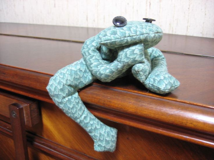 a stuffed frog sitting on top of a wooden dresser