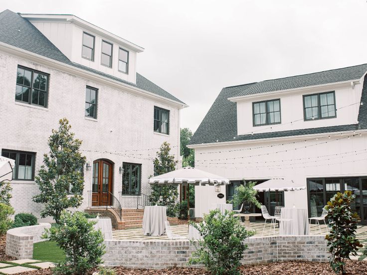 an outside view of a white house with tables and umbrellas