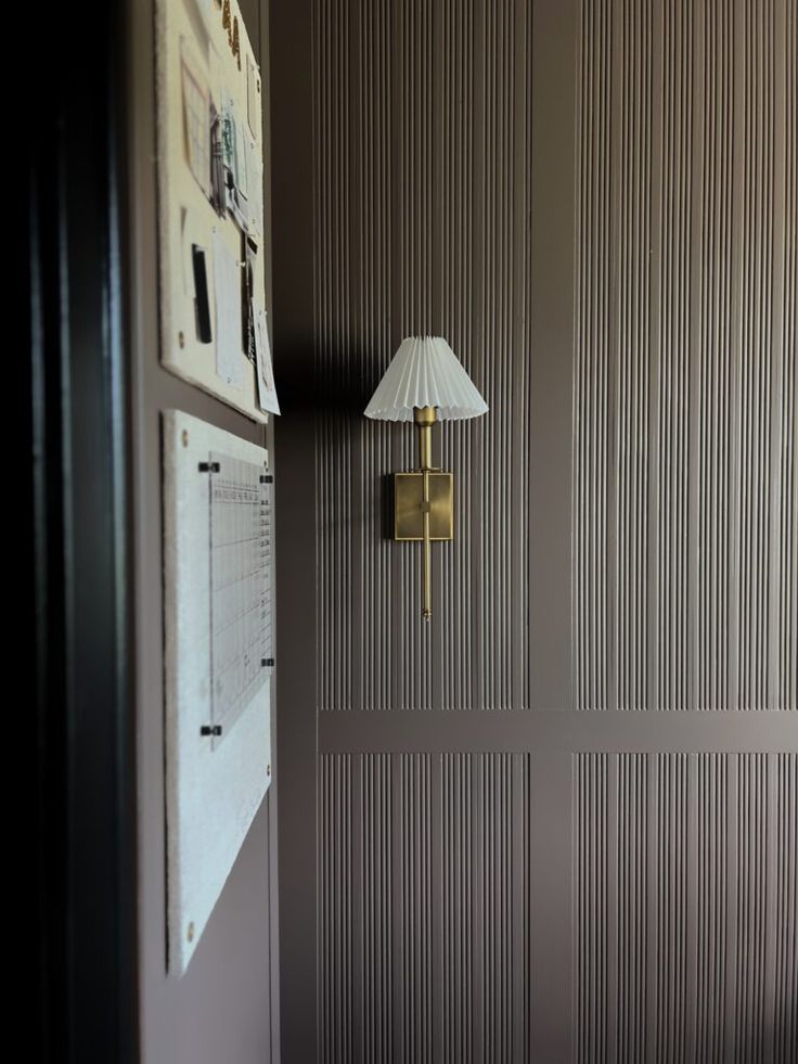 a lamp is on the wall next to a bed in a room with striped walls