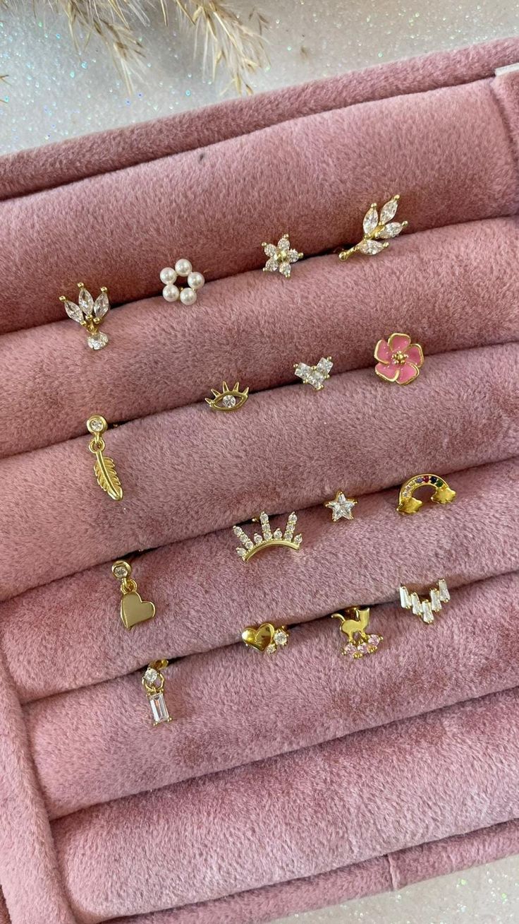 six pairs of gold earrings on pink velvet