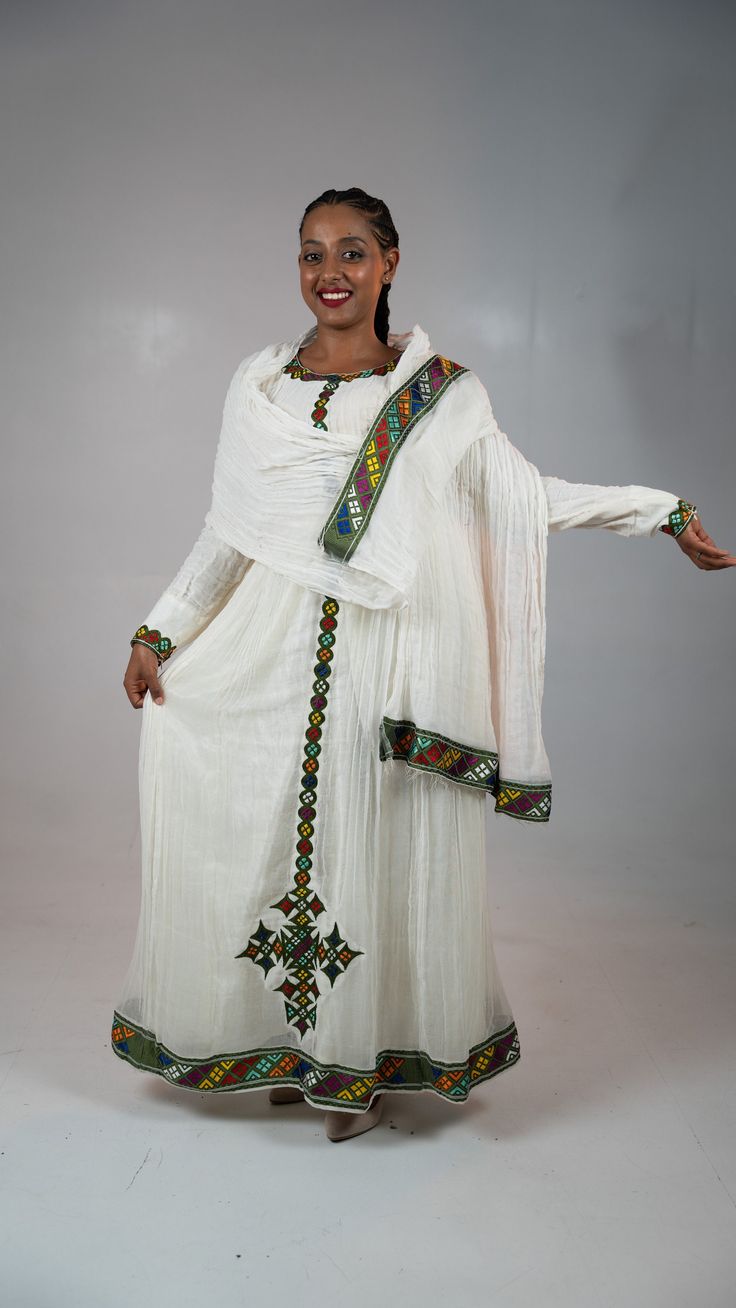 Simple Ethiopian dress with a beautiful trim and hand embroidery. This dress comes with full netela (two panel 2m scarf). Model is wearing a A/M but It can be custome made in any size. please and your measurement when you place your order and also your phone number. phone numebr is required on the shipping form. Fitted Anarkali Dress With Traditional Embroidery, Anarkali Dress With Embroidered Border For Traditional Ceremonies, Floor-length Dress With Dupatta For Traditional Ceremonies, Floor-length Dress With Dupatta For Ceremonies, White Dress With Resham Embroidery And Traditional Drape, Fitted Floor-length Sets With Embroidered Border, Fitted Embroidered Dress With Traditional Patterns For Festive Occasions, Festive Dress With Embroidered Border And Traditional Drape, Fitted White Dress With Traditional Patterns