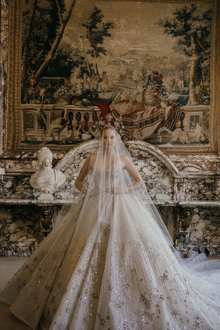 a woman in a white wedding dress standing next to a wall with a painting on it