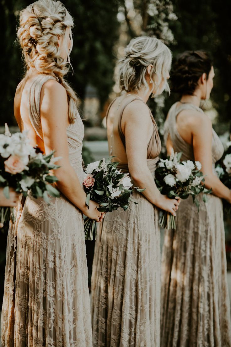 the bridesmaids are wearing gold dresses and holding bouquets in their hands as they look at each other