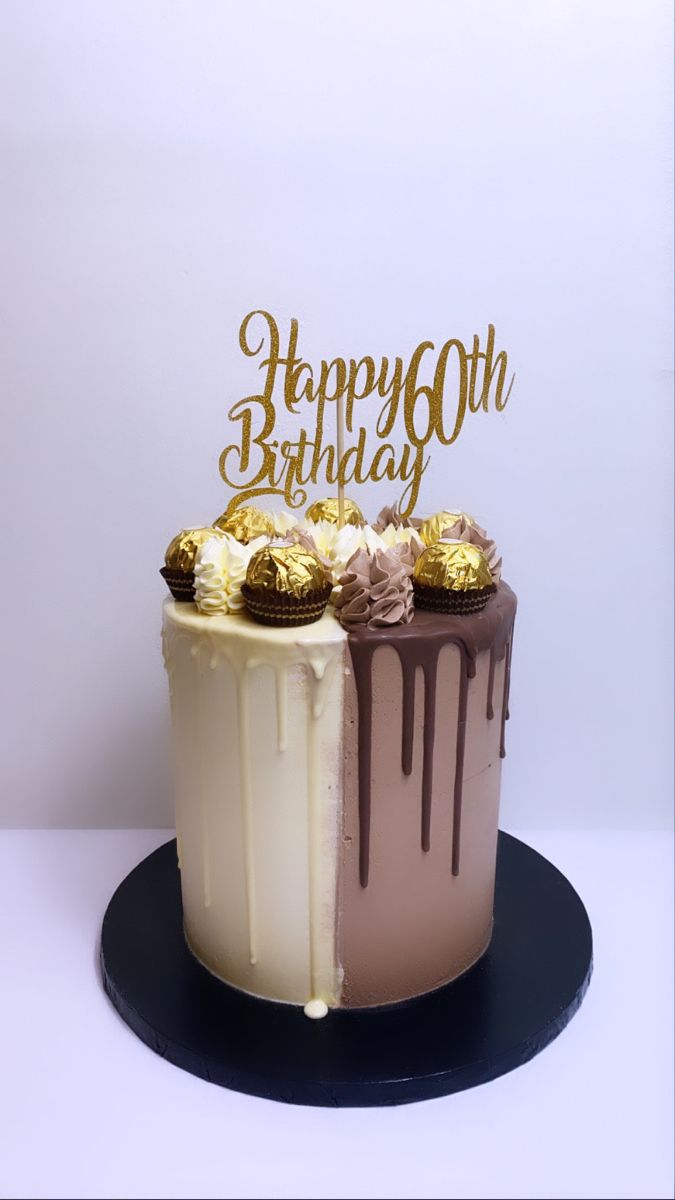 a birthday cake with white frosting and chocolate icing on top, sitting on a black plate