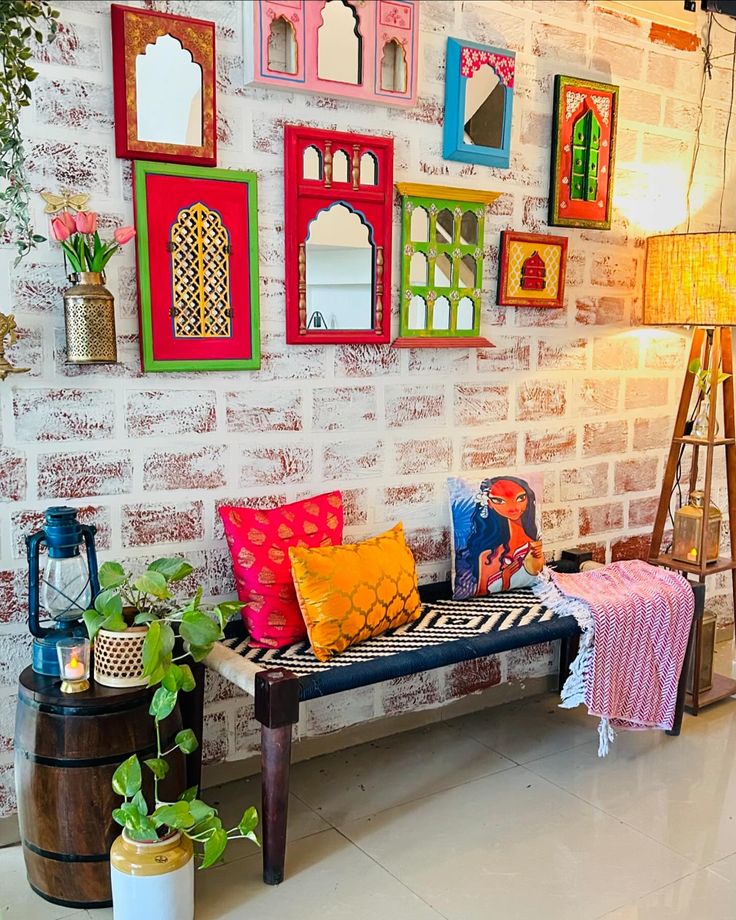 a brick wall with many different colored mirrors on it and a bench in the middle