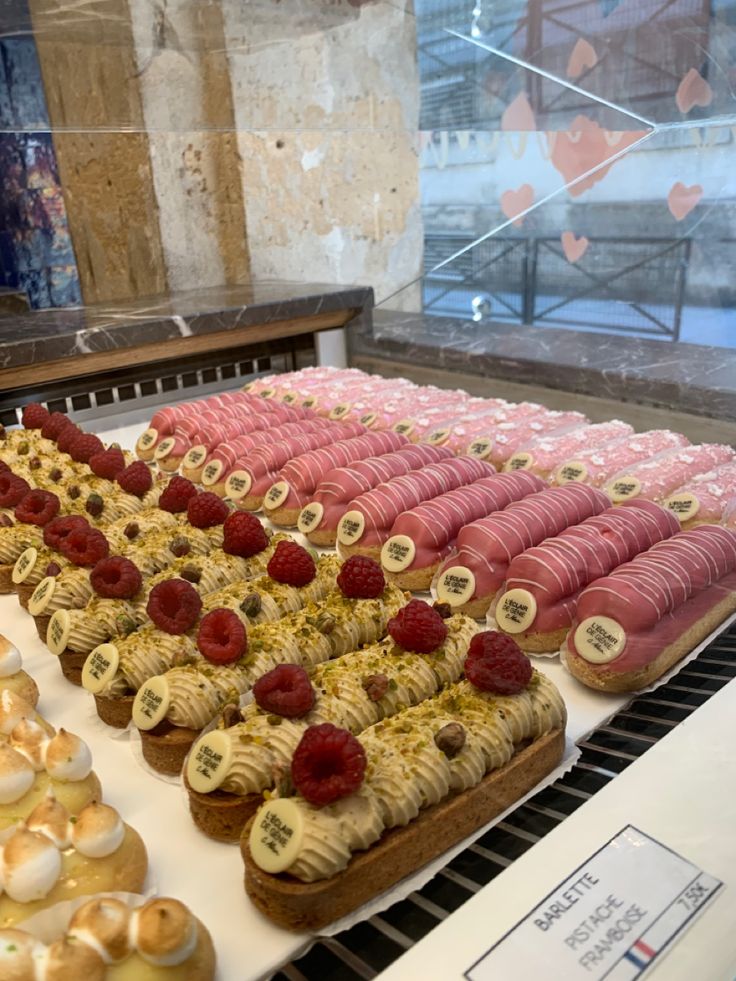 there are many pastries on display in the case at this store, including raspberries and bananas