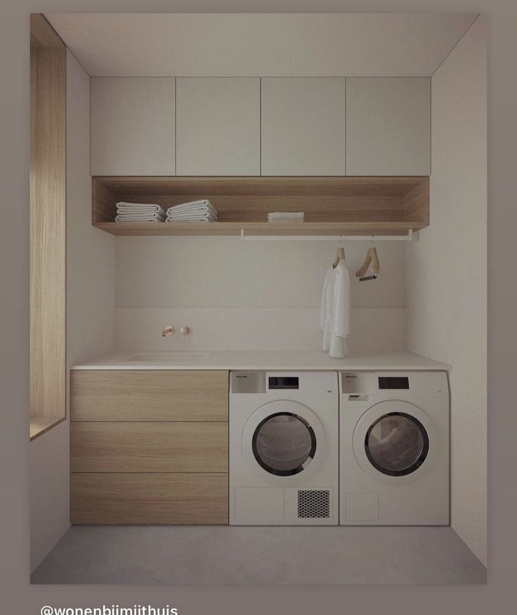 a washer and dryer in a small room with white cabinets on the wall