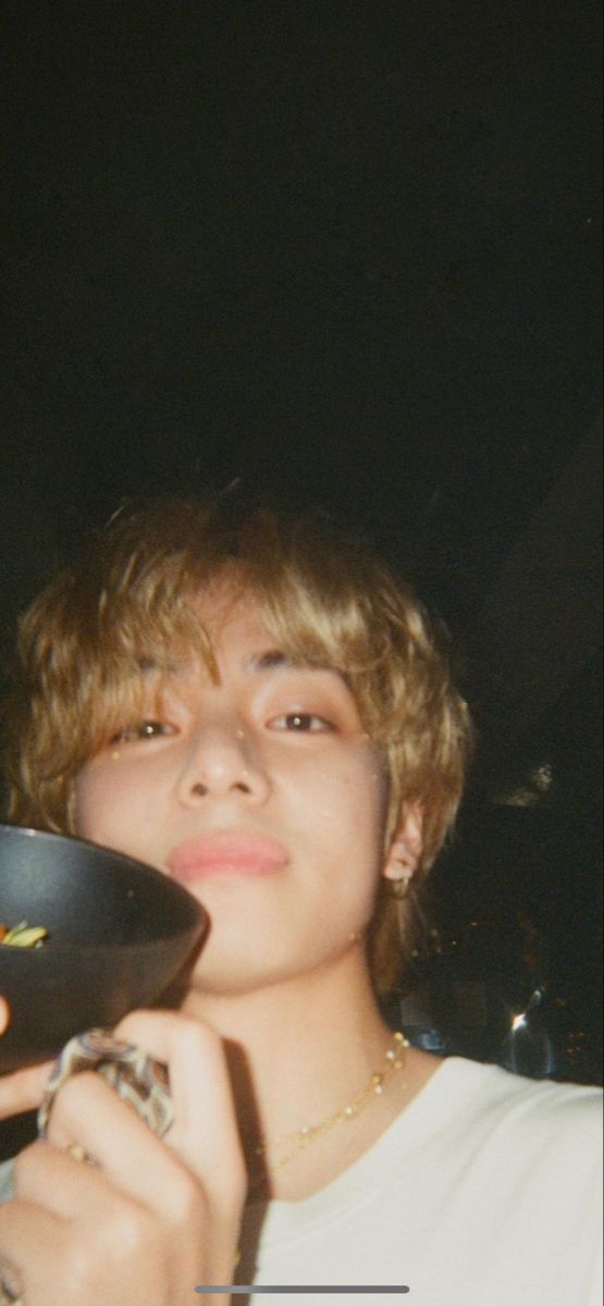 a young man holding a black bowl in his hand