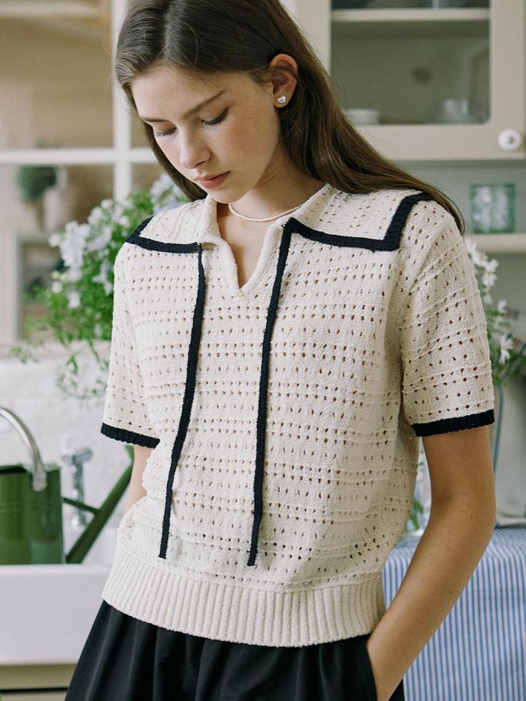 This product showcases a crochet-trimmed knit top, featuring a sophisticated contrast trim along the collar and front. The open-weave crochet design adds a unique textural element, while the short sleeves and lightweight fabric make it ideal for warmer weather or layering. Its relaxed fit allows for comfortable movement, creating an effortless, stylish look. - This top features a contrasting trim that frames the neckline and placket, providing a sharp, tailored edge.- The crochet pattern not only serves as an elegant detail but also ensures breathability and comfort.- Its short sleeve design is perfect for creating a polished look without the warmth of long sleeves.- The ribbed hem adds a cozy finish to the top, keeping it in place throughout the day. Chic Short Sleeve Crochet Top With Pointelle Knit, Beige Pointelle Knit Short Sleeve Top, Beige Short Sleeve Pointelle Knit Top, Short Sleeve Crochet Knit Top, Beige Crochet Top With Open Knit Short Sleeve, Beige Short Sleeve Cotton Crochet Top, Beige Open Knit Short Sleeve Top, Beige Short Sleeve Open Knit Top, Knit Tops With Crochet Trim And Short Sleeves