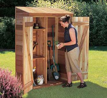 a woman is standing in a wooden shed with her garden tools and gardening equipment inside