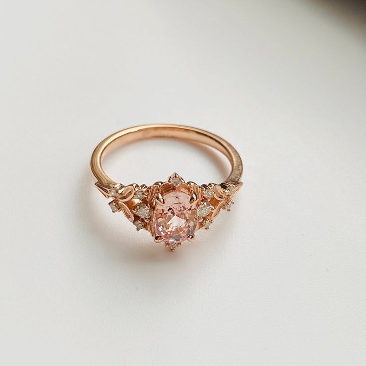 a pink diamond ring sitting on top of a white table