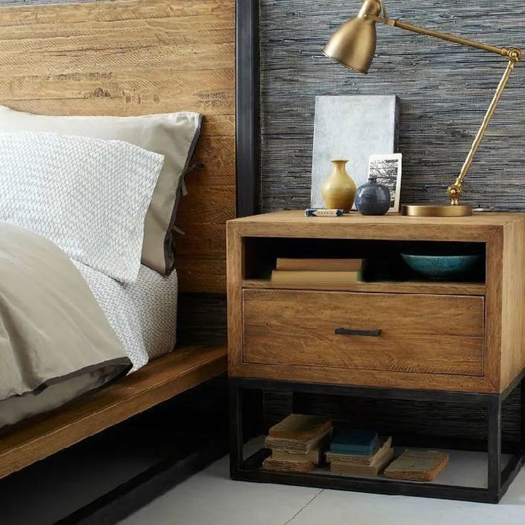 a bed with a wooden headboard and night stand next to a nightstand that has books on it