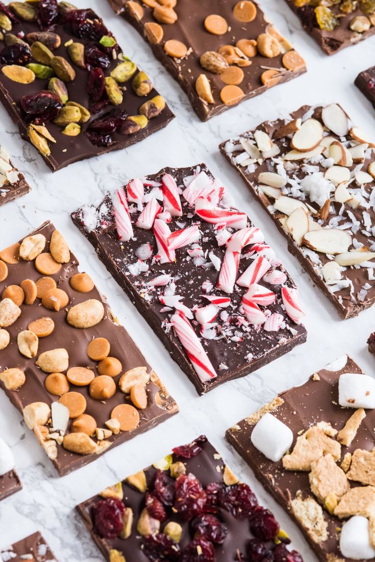 many different types of chocolates and nuts are arranged on a white surface with candy canes