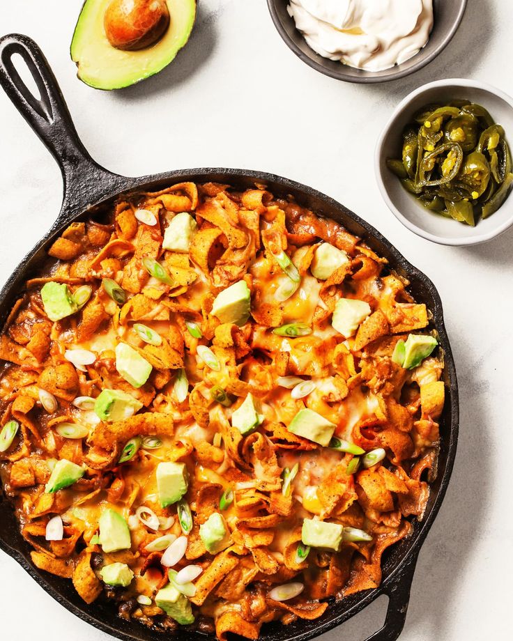 a skillet filled with mexican food next to some guacamole and sour cream