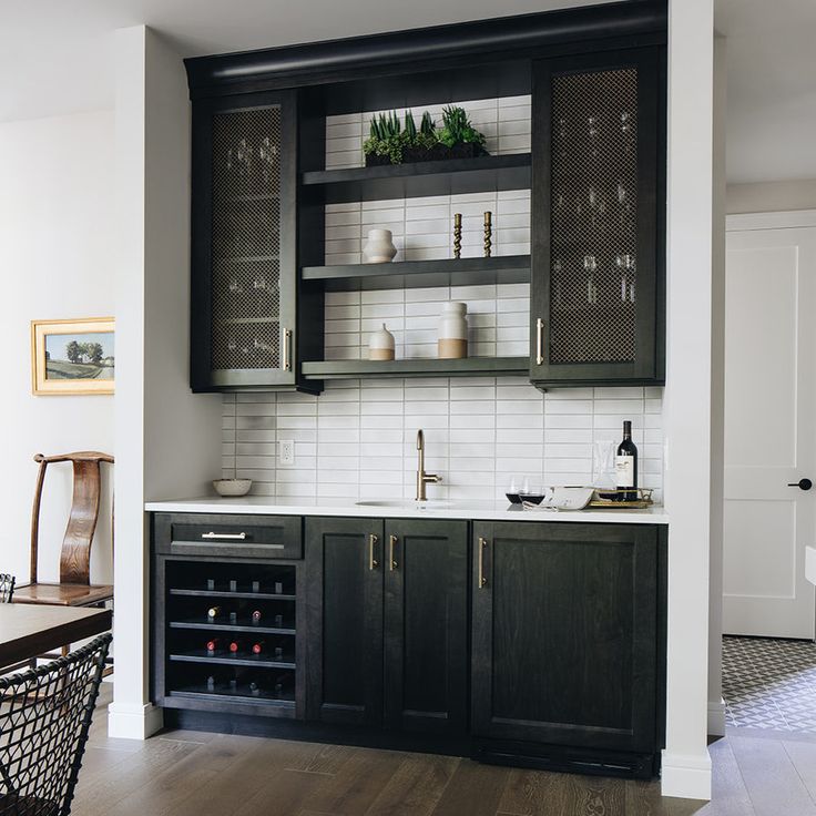 a kitchen with black cabinets and wooden floors