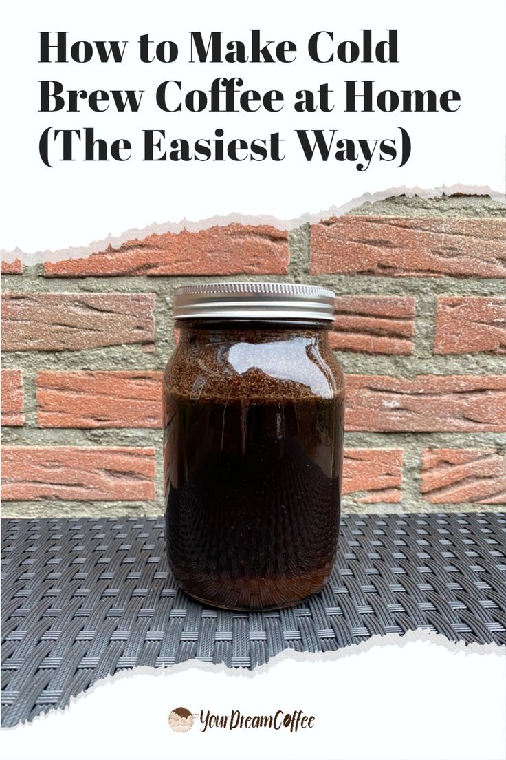 a jar filled with coffee sitting on top of a table next to a brick wall