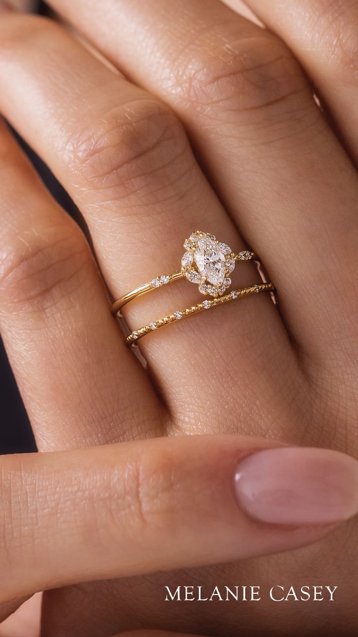 a woman's hand with two gold rings on it and one diamond ring in the middle