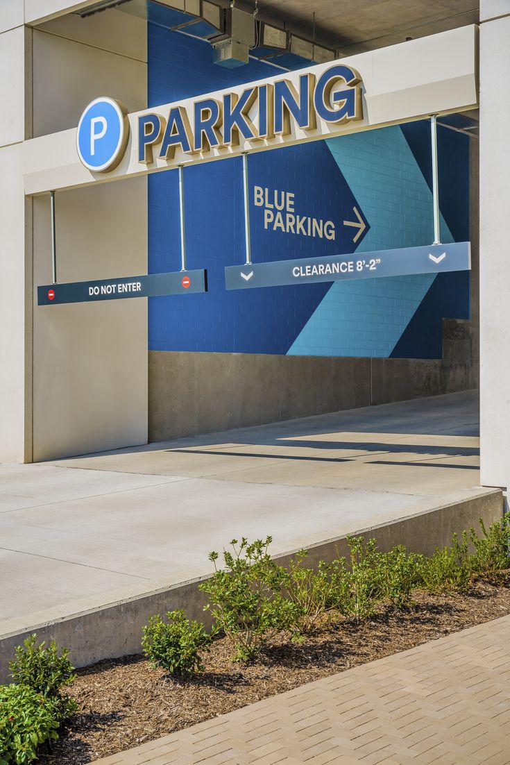 a parking garage with blue and yellow signs on it's front door, next to a sidewalk