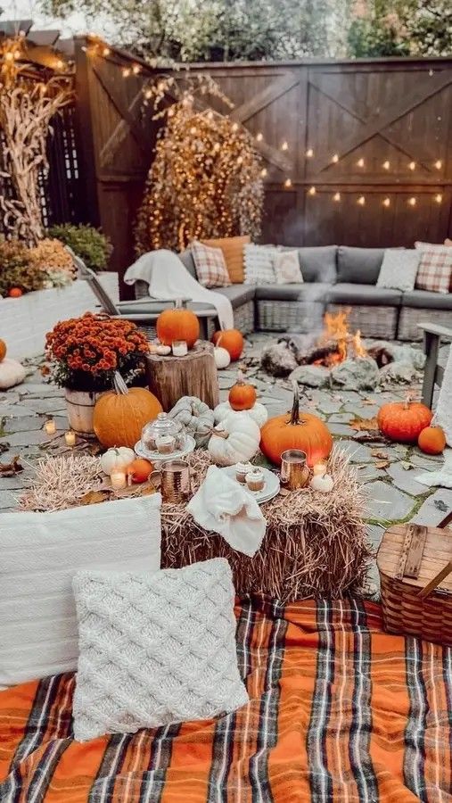 an outdoor table with pumpkins and hay in the center, surrounded by candles and decorations