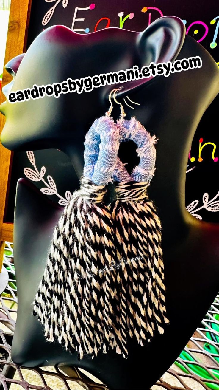 a black mannequin head with white feathers and a ring on it's neck