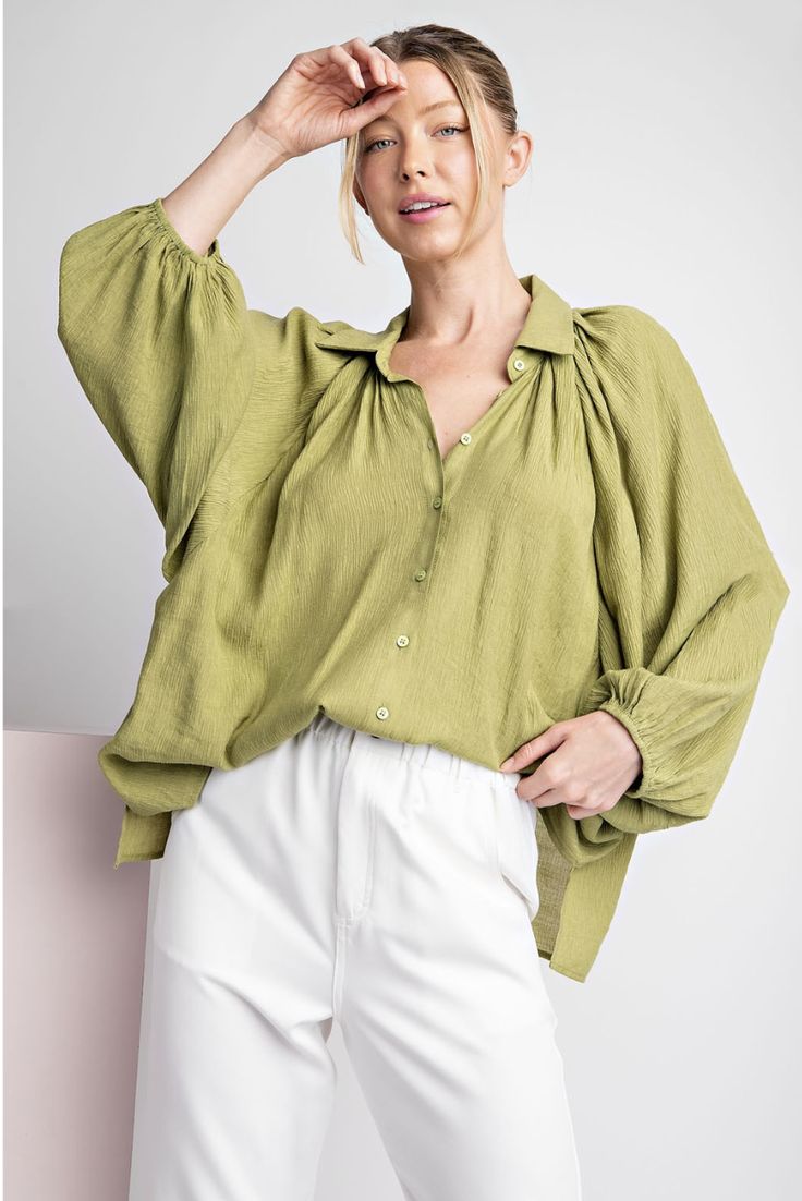 Solid long sleeve blouse top featuring a button down front, elastic cuffs for a bubble sleeve effect, two side slits, a collared neckline and is pinched for extra detail. beautiful avocado color Elevate your wardrobe with this playful blouse. With a button down front and elastic cuffs that create a bubbly sleeve effect, it's unique and trendy. Featuring subtle details like side slits and a collared neckline, this blouse adds flair to any outfit. Plus, the beautiful avocado color is sure to turn Versatile Spring Blouse With Button Closure, Spring Bishop Sleeve Blouse With Button Cuffs, Chic Day Out Blouse With Bishop Sleeves, Chic Bishop Sleeve Blouse For Day Out, Chic Blouse With Bishop Sleeves For Day Out, Long Sleeve Blouse With Button Closure For Day Out, Casual Lantern Sleeve Tops With Button Cuffs, Trendy Balloon Sleeve Blouse For Day Out, Chic Green Tops With Gathered Sleeves