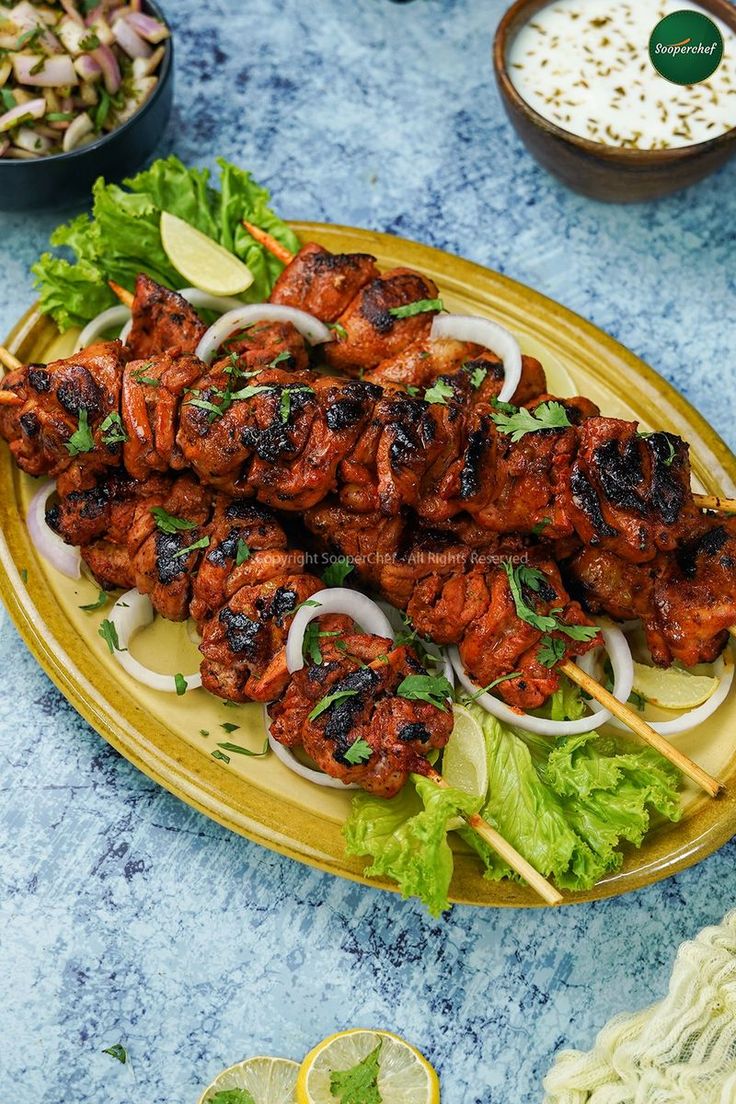 chicken skewers with onions and lettuce served on a yellow platter