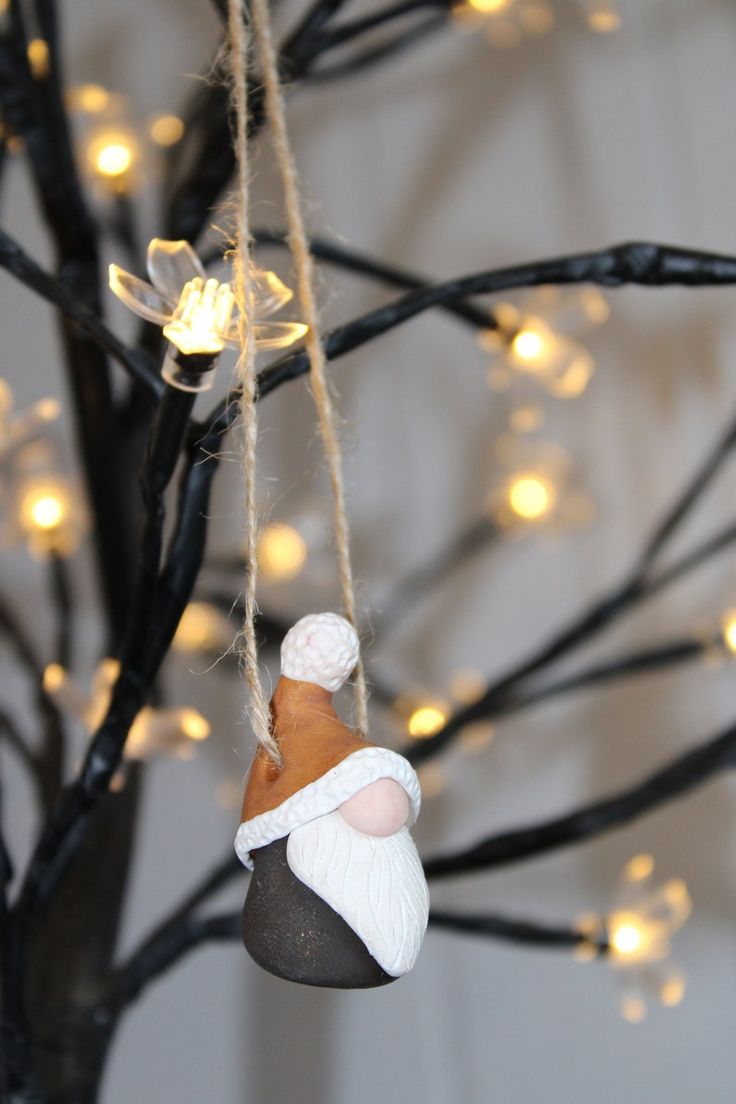 a christmas ornament hanging from a tree with lights on the branches behind it