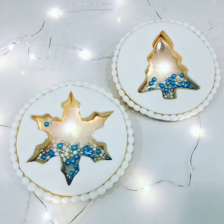 two decorated cookies sitting on top of a white plate covered in blue and gold decorations