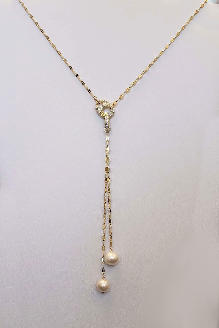 Our Pearl Lariat Necklace is a stunning piece of jewelry designed to make a bold statement. This necklace features 2 freshwater pearls handwrapped onto a gold sequin chain. crafted from high-quality materials, creating a luxurious and contemporary look. The lariat style adds a touch of elegance and versatility, allowing you to adjust the length and drape to suit your outfit and preference. The focal point of this necklace is our stunning carabiner pave clasp that adds a stunning contemporary fla Elegant White Gold Lariat Chain Necklace, Pearl Charm Lariat Jewelry, Elegant Lariat Chain Necklace With Lobster Clasp, Pearl Lariat Necklace With Chain, Elegant Gold Lariat Necklace With Lobster Clasp, Pearl White Long Necklace With Clavicle Chain, Pearl White Pearl Jewelry With Chain, Luxury Pearl Lariat Necklace, Luxury Lariat Necklace With Lobster Clasp