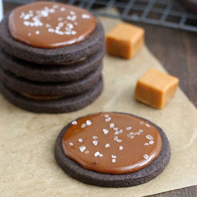 cookies with chocolate frosting and white sprinkles are on a piece of wax paper