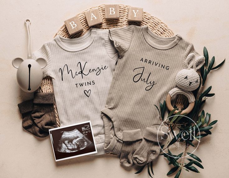 two baby ones sitting next to each other on top of a wooden table with an infant's photo