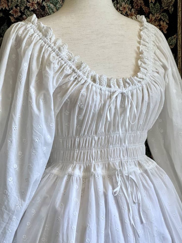 The perfect base to any historically inspired outfit, our 100% cotton smocked chemise dress is sure to please! This stunning gown is made of floral embroidered cotton, and trimmed with floral cotton lace. It features smocked shirring all the way around the bodice, drawstrings for size adjustment, large billowy bishop sleeves with bell sleeve cuffs, and a full skirt big enough to fit a petticoat or a crinoline. This chemise is light, sheer, and flowy; perfect for wearing alone on a summer day, as 18th Century Dress Simple, 18th Century Dress, Billowy Sleeves, Muslin Dress, Chemise Dress, Gunne Sax Dress, Fairytale Dress, Medieval Fashion, Stunning Gowns