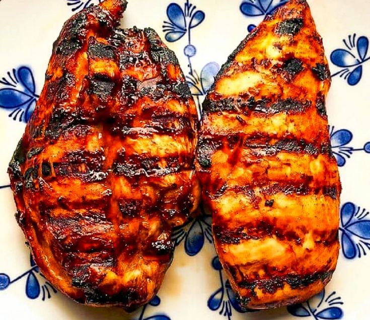 two pieces of grilled meat sitting on top of a blue and white plate