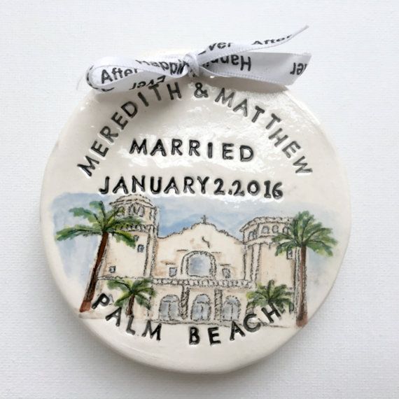 a white ceramic ornament with a palm tree and building on it's side