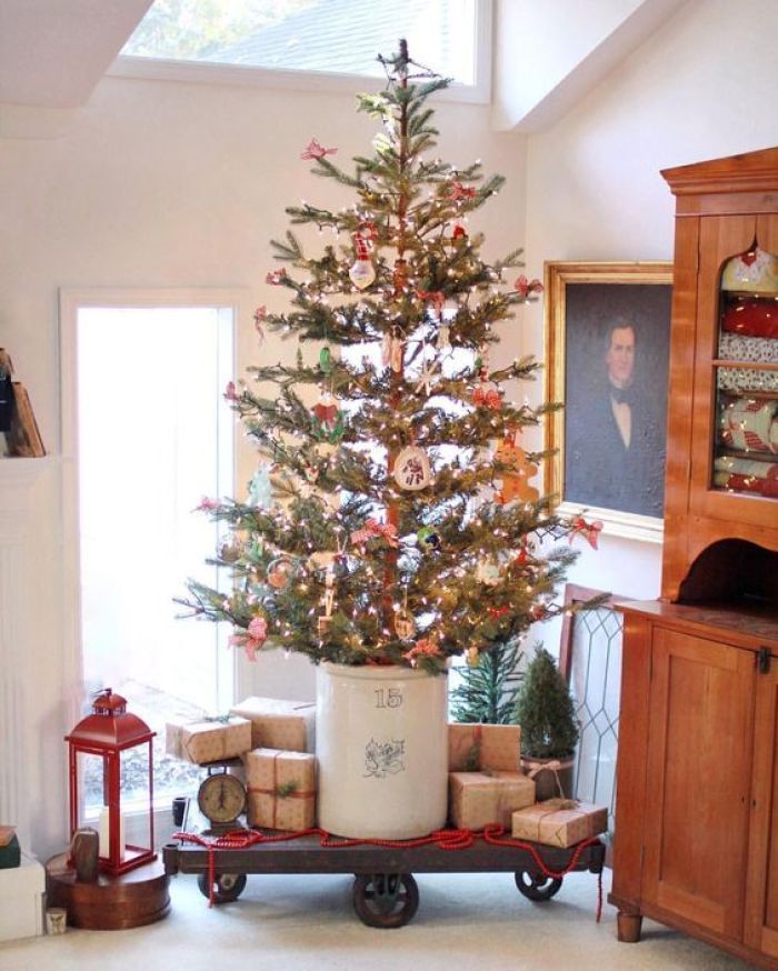 a small christmas tree in a pot with presents on the bottom and an old fashioned wagon