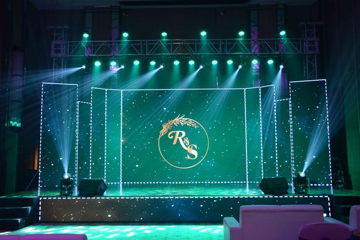 an empty stage with green lighting and white chairs