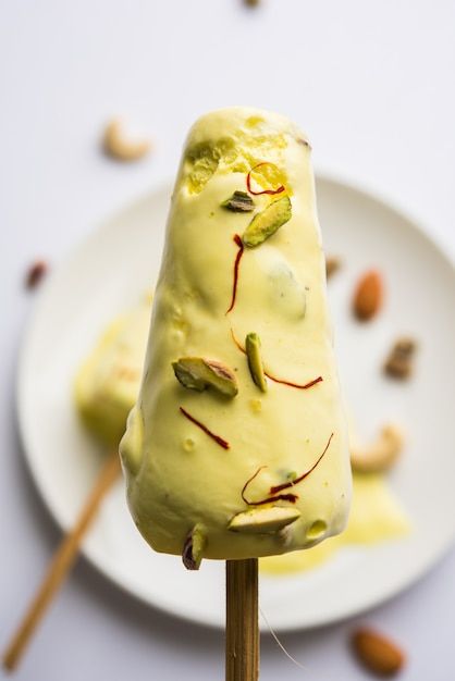 an ice cream on a stick with pistachio and almonds around the top