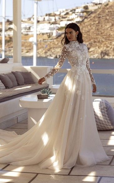 a woman in a wedding dress standing on a patio near a couch and table with pillows