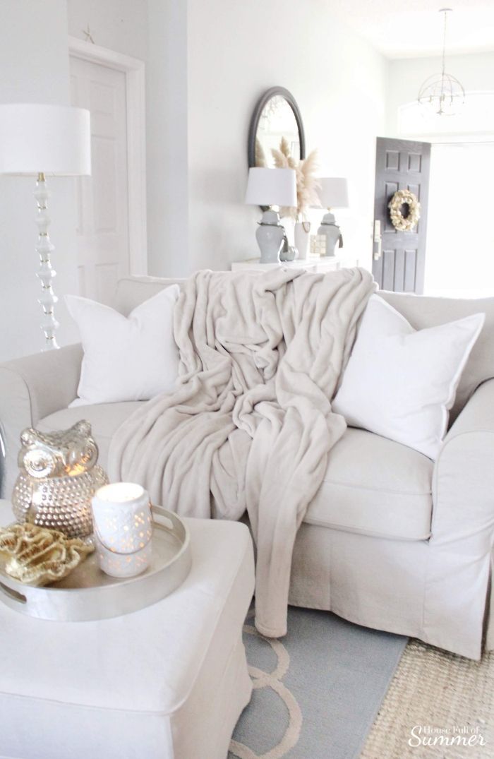 a living room with a white couch and coffee table in the corner, covered by a blanket