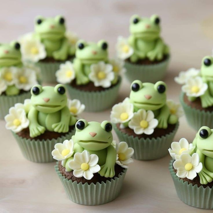 small green cupcakes decorated with flowers and frog figurines