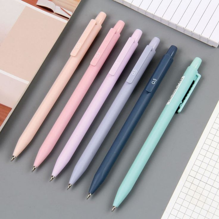 four different colored pens sitting next to each other on top of a table with notebooks