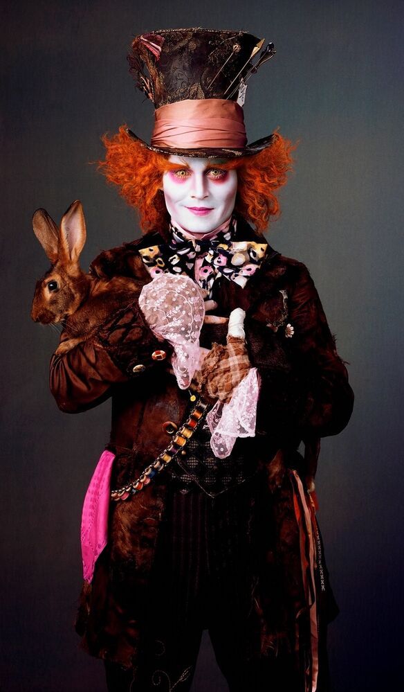 a man with red hair wearing a top hat and holding a rabbit in his arms